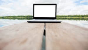 blank laptop on the wooden table with nature background
