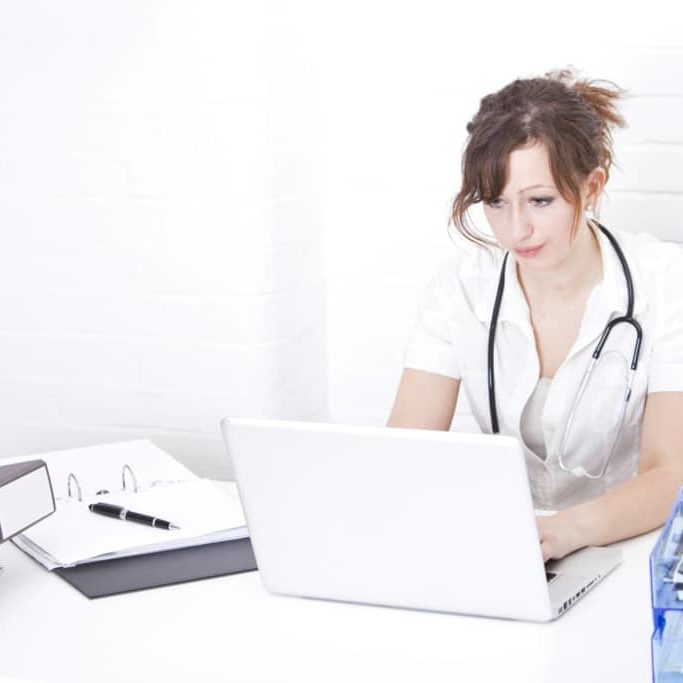 Young female doctor using laptop at desk in clinic Young female doctor using laptop at desk in clinic